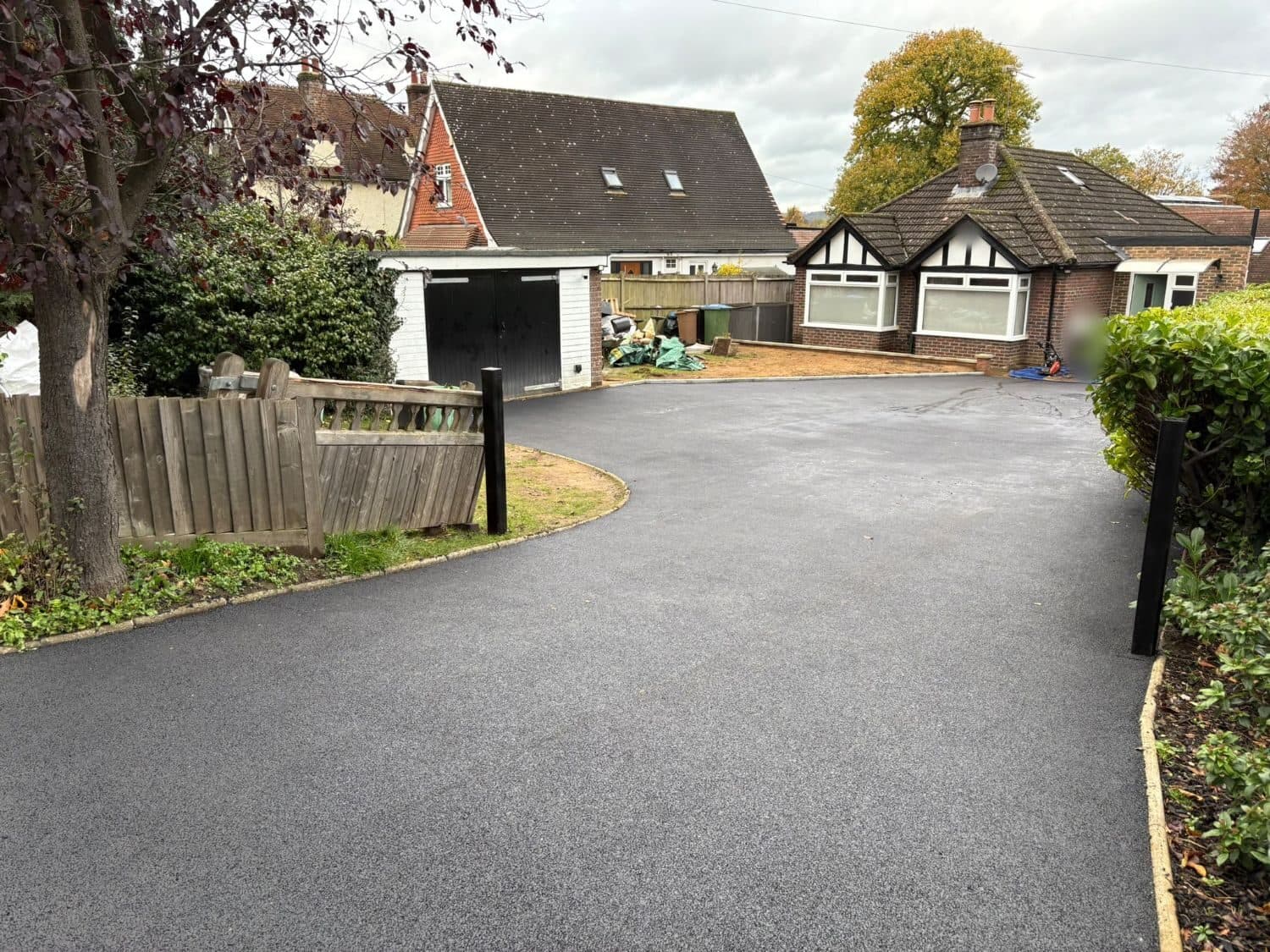 Long curving tarmac driveway leading from the road up to a brick bungalow